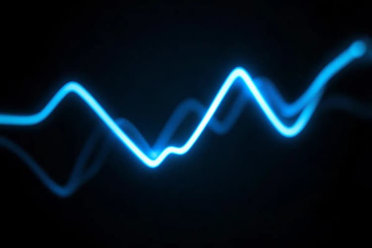 Um gráfico de linha abstrato feito de fios de luz azul brilhante em um fundo escuro.